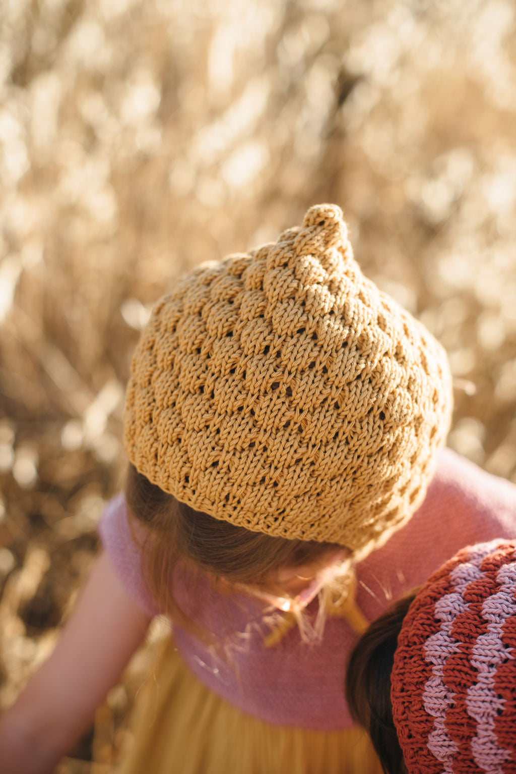 Niña con capota de punto bubbles color mostaza de MöMMOT