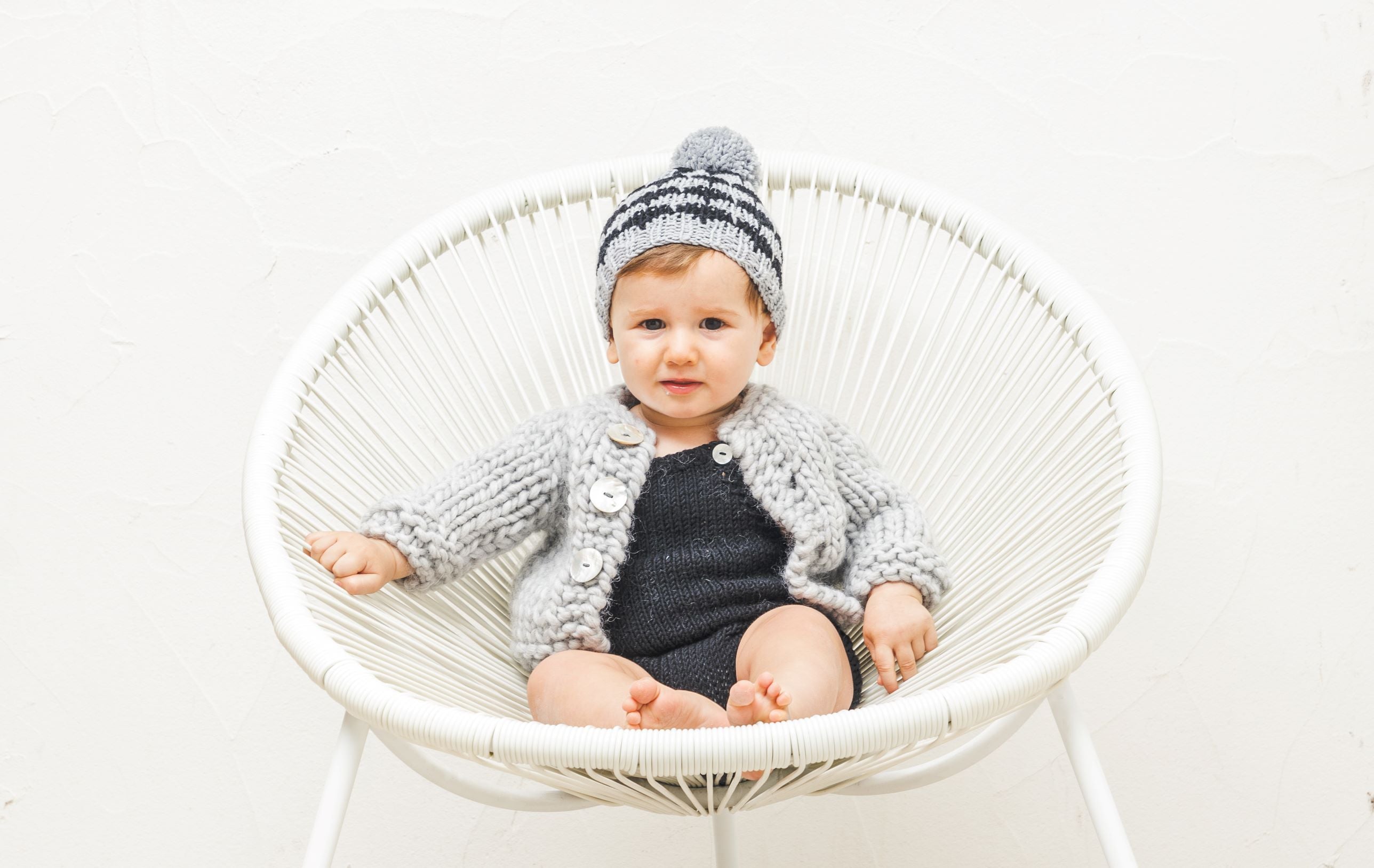 Niño con gorro de punto con pompón tejido a mano con patrón de MöMMOT