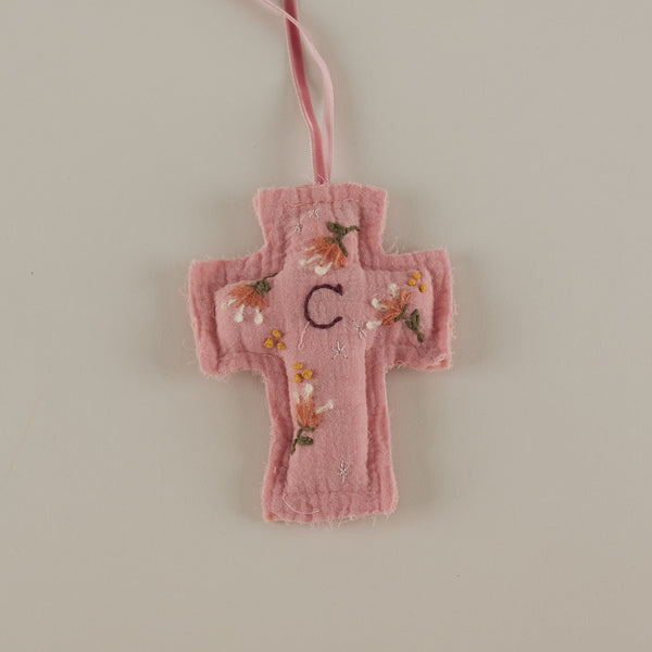 Cruz rosa bordada a mano con inicial para cuna